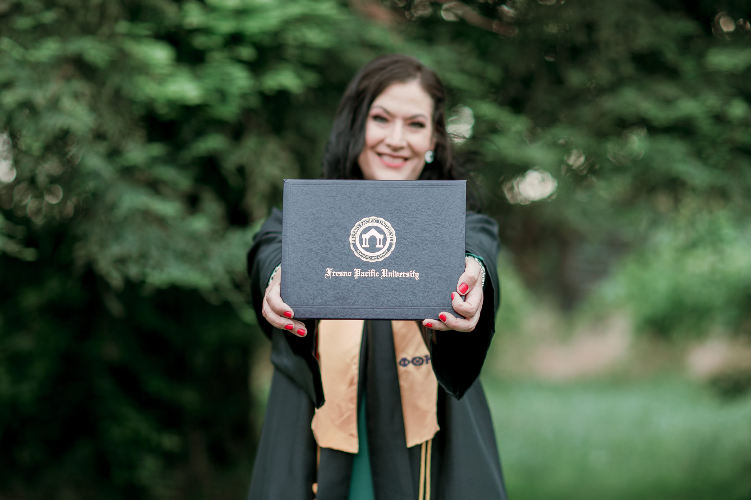 a woman shows off her diploma during grad photos