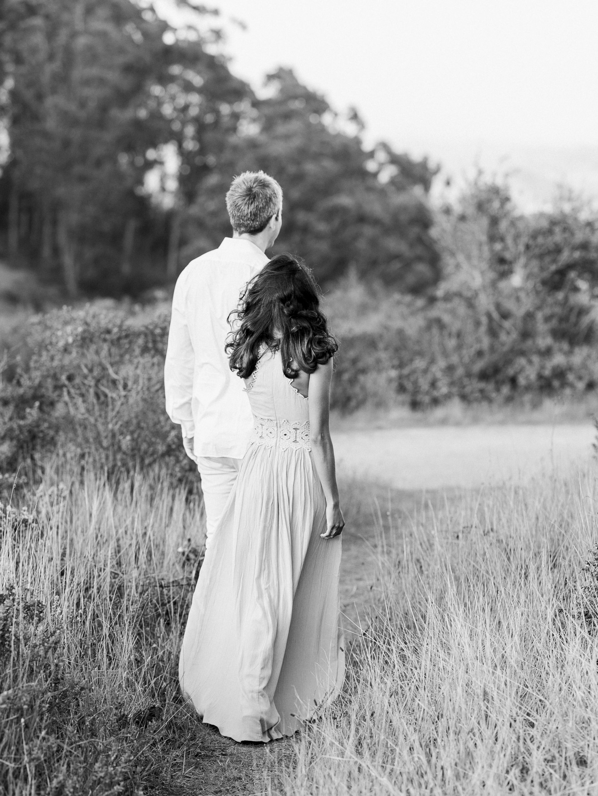 a black and white photo of a couple walking through the prairie during their Marin County engagement photos